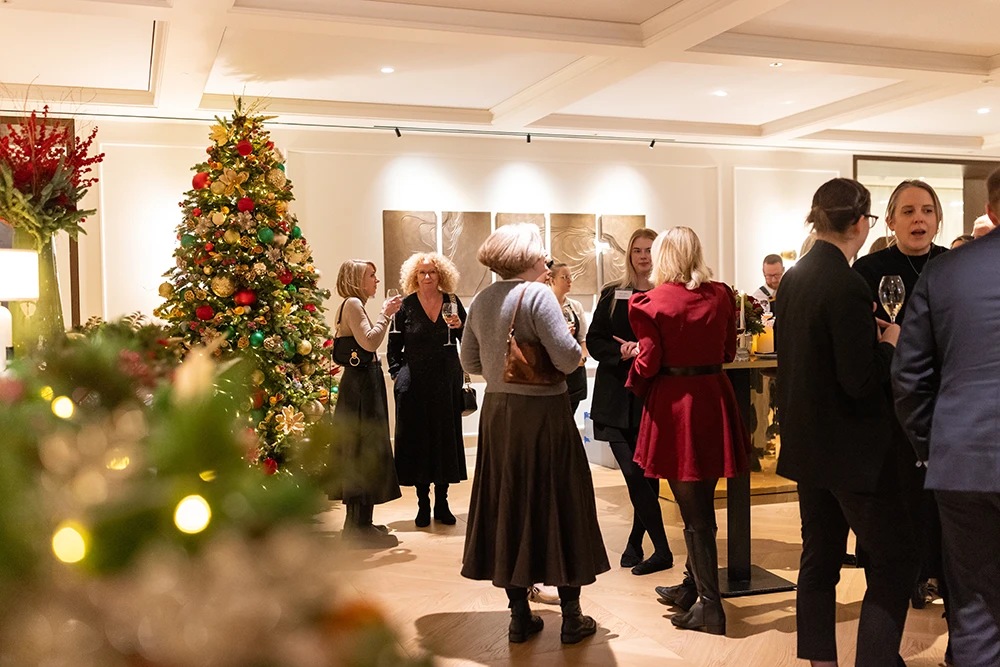 Guests mingling with drinks beside a decorated Christmas tree at a corporate Christmas networking event