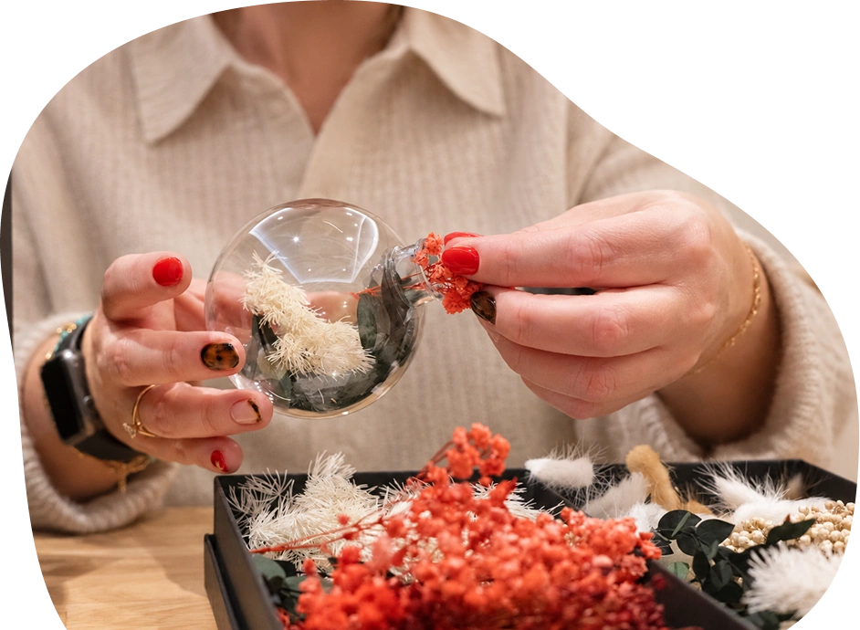 Botanical Christmas Bauble Workshop Guest filling a glass Christmas bauble with dried flowers during a creative workshop