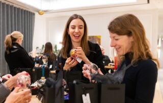Two women laughing as they fill their baubles with dried flowers at a corporate Christmas bauble workshop