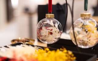 Personalised Christmas bauble filled with white dried flowers, red petals and stars, with a gold initial and red velvet ribbon