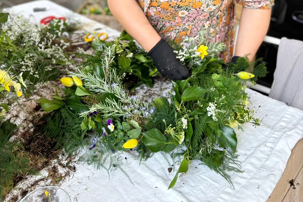 Spring Wreath Workshop Guest making a spring wreath with fresh flowers and green foliage